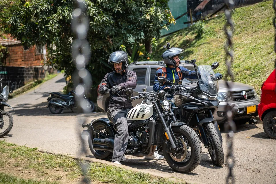Dos motociclistas conversando en sus motos en una calle empinada