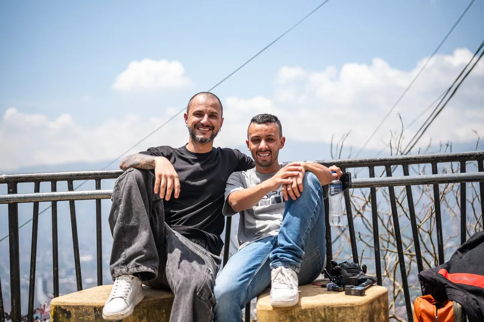 Dos hombres sentados en un mirador, sonriendo