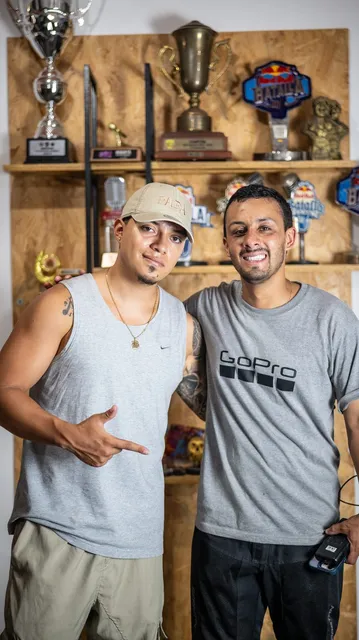 Dos hombres posando frente a una repisa llena de trofeos